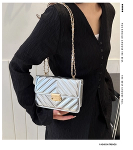 Detail of silver quilted handbag with metallic V-stitch pattern and gold chain strap