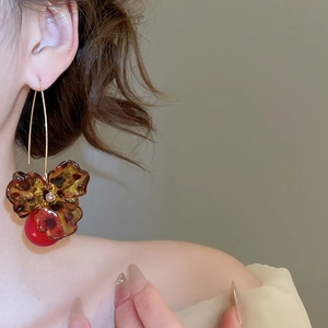 Close-up of vintage flower leopard print earrings with amber petals and red sphere pendant