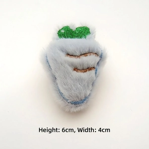 Close-up of 6cm plush carrot accessory with blue faux fur texture and green embroidery