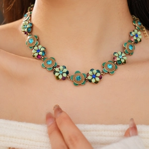 Close-up of vintage flower necklace with green and blue enamel petals and rhinestones