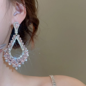 Gros plan de boucles d'oreilles pendantes roses avec cristaux et pompons argentés