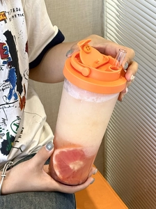 Detail view of Tritan straw cup with orange lid and grapefruit slice drink inside