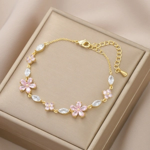 Detailed close-up of gold flower bracelet with pink petals and marquise zircons