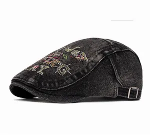 Close-up of black denim beret featuring colorful embroidery and silver metal buckle