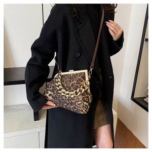 Detail of vintage leopard print shell bag with chunky gold chain on a black coat