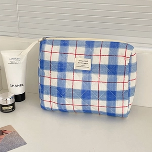 Detail of blue and white plaid quilted toiletry bag with red lines and zipper closure