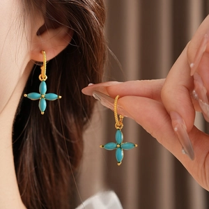 Gold plated four leaf clover stud earrings with turquoise stones worn by a model