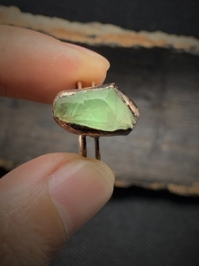 Macro detail of a vintage adjustable ring featuring an irregular green raw gemstone