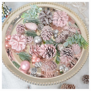 Close-up of pink and silver pine cones with pearls on a golden tray for Christmas decor