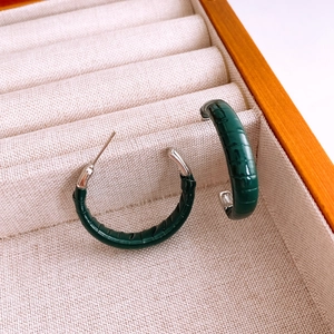 Détails macro des boucles d'oreilles créoles en cuir vert foncé à motif crocodile