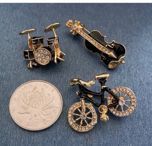 Detailed set of violin, drum and bicycle brooches with black enamel and rhinestones