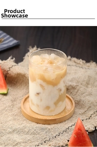Primer plano de vaso de vidrio con rayas verticales y café helado en posavasos de madera