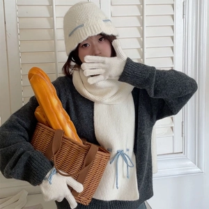 Detail of cream knit winter set with blue bow accent including hat, scarf, and gloves