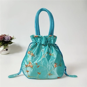 Detailed close-up of blue satin drawstring handbag with exquisite floral embroidery pattern