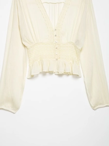 Detailed view of the deep V-neckline and intricate lace embroidery on the cream blouse