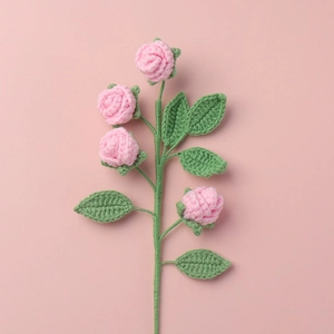 Detail of four handmade knitted pink roses with green leaves on soft background