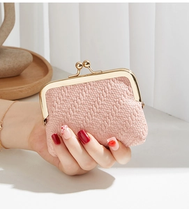Close-up of pink woven coin purse with vintage gold metal clasp being held by hand