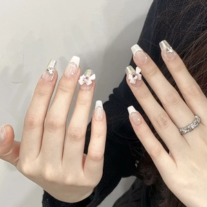 Detailed view of handmade coffin press-on nails with 3D bows and pink rhinestones