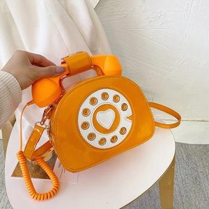 Detailed view of vintage orange telephone bag with glossy patent leather and heart dial