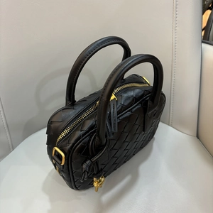 Close-up of mini black woven leather bag with gold-tone hardware and zippers
