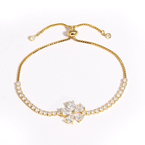 Détail d'un bracelet doré ajustable avec pendentif fleur et pierres de zircon claires