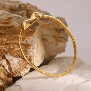 Detail van een gouden gedraaide armband met sprankelende diamanten op een ruwe steen
