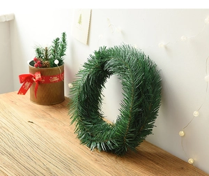 Close-up of artificial green pine needle Christmas garland on a rustic wooden table surface