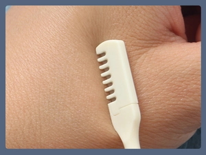 Close-up of portable white dual-head nose hair trimmer tool shown on hand skin