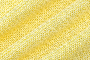 Detailed macro view of bright yellow hollow knit fabric texture with breathable mesh structure