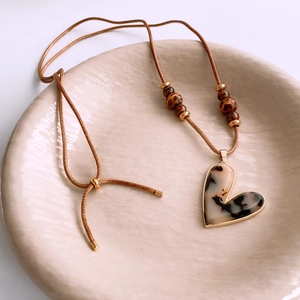 Detailed close-up of a heart leopard print pendant necklace on a ceramic display plate