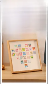 Square wood frame with heart-shaped collage of miniature hand-painted art on desktop