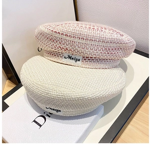 Detail of tweed and woven beret hats with brand label patch on structured fabric