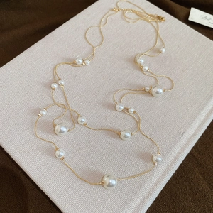 Detail of elegant double-layered pearl necklace with golden chains on textured background