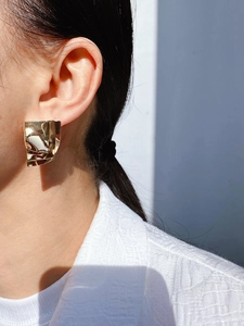 Close-up of golden geometric multi-layer mirror metal square earrings worn on model