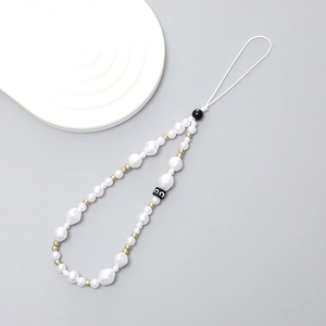 Elegant pearl phone wrist strap with gold and black beads on a white wave tray