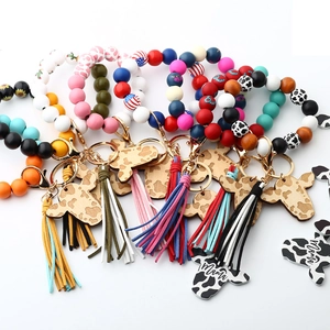 Detail of cow-print wood bead keychain with leather tassel and Mama engraved charm