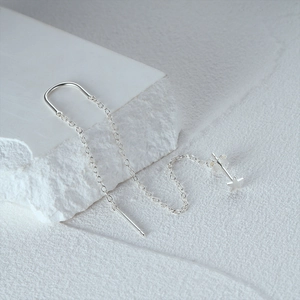 Macro detail of S925 sterling silver star earring with long tassel chain on white stone