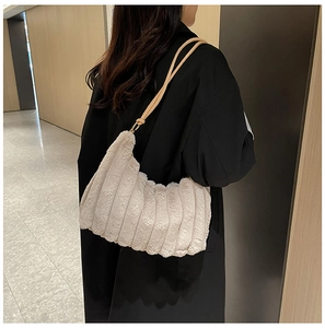 Borsa a mano in peluche beige con trama a coste e catena dorata su cappotto nero