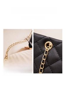 Détail de la texture en cuir noir matelassé et de la chaîne en métal doré du sac à bandoulière