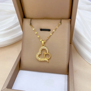 Gold titanium steel necklace with heart pendant and ring detail on a satin background