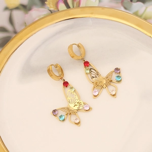 Gold butterfly drop earrings with colorful rhinestones on a white ceramic plate