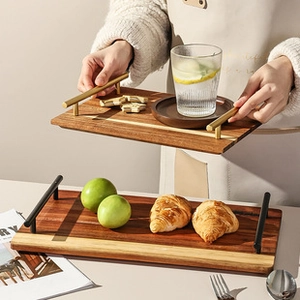 Detail of rectangular wooden serving trays with black and gold metal handles for home use