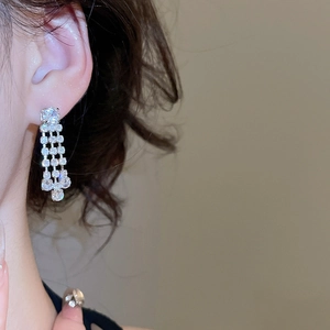 Close-up of sparkling cubic zirconia square fringe tassel earrings worn by a model