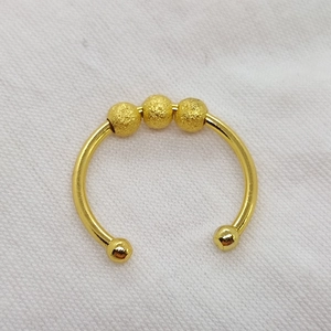 Macro view of golden horseshoe open ring featuring textured beads on a white surface