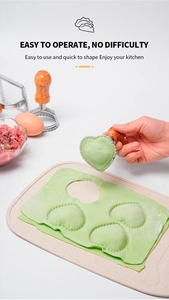 Detail of heart-shaped pasta cutter with ergonomic wood handle making green ravioli