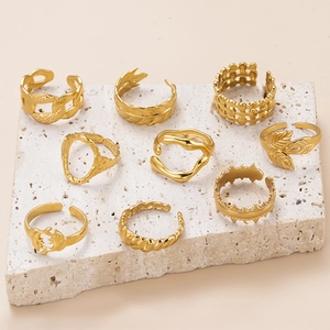 Set of 9 gold leaf and chain style adjustable stainless steel rings on a stone display