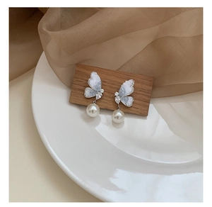 Detailed view of silver butterfly earrings with gradient crystal wings and hanging pearl