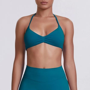 Detail view of teal halter neck sports bra with subtle pleat design and high waist leggings