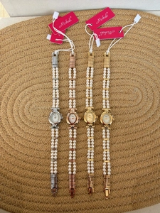 Detail view of oval pearl bracelet watches in four metallic finishes on woven mat