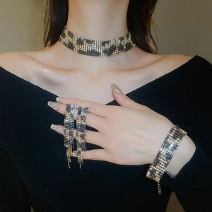 Close-up of leopard print rhinestone necklace, fringe earrings, and bracelet set on model
